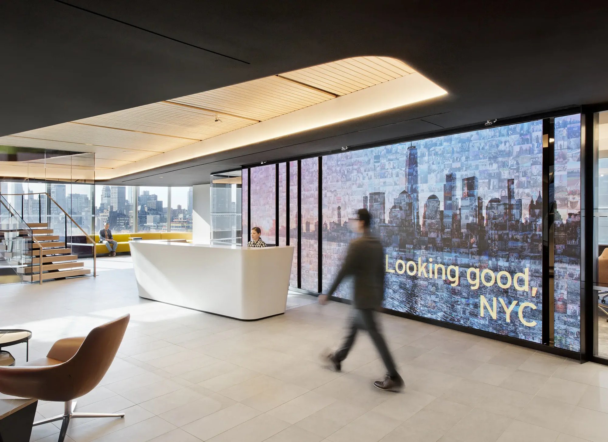 A person walking by a large video wall within an office space.