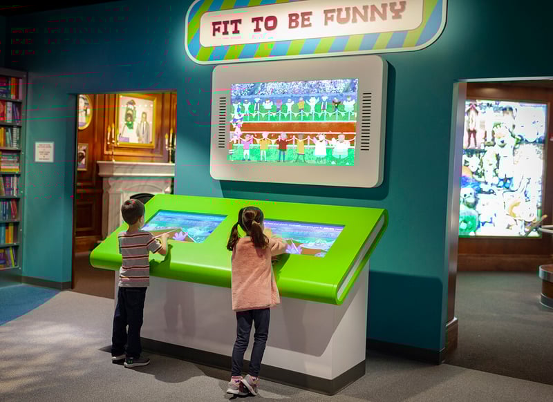 Two young visitors to the Mascot Hall of Fame interacting with a touchscreen game.