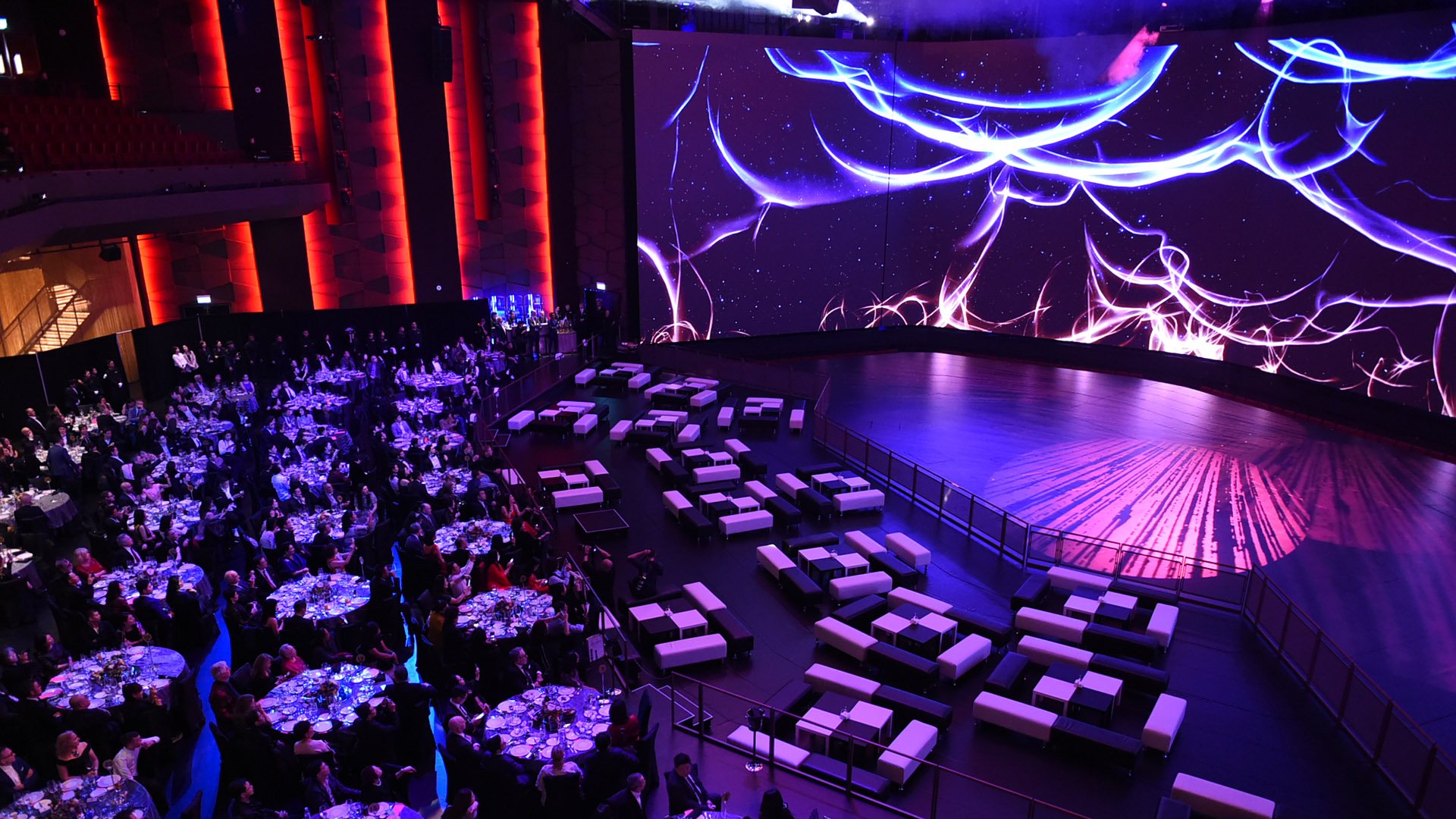 The Dynamic Theater at MGM COTAI, large LED walls anchor the room surrounded by tables and chairs for a large event.
