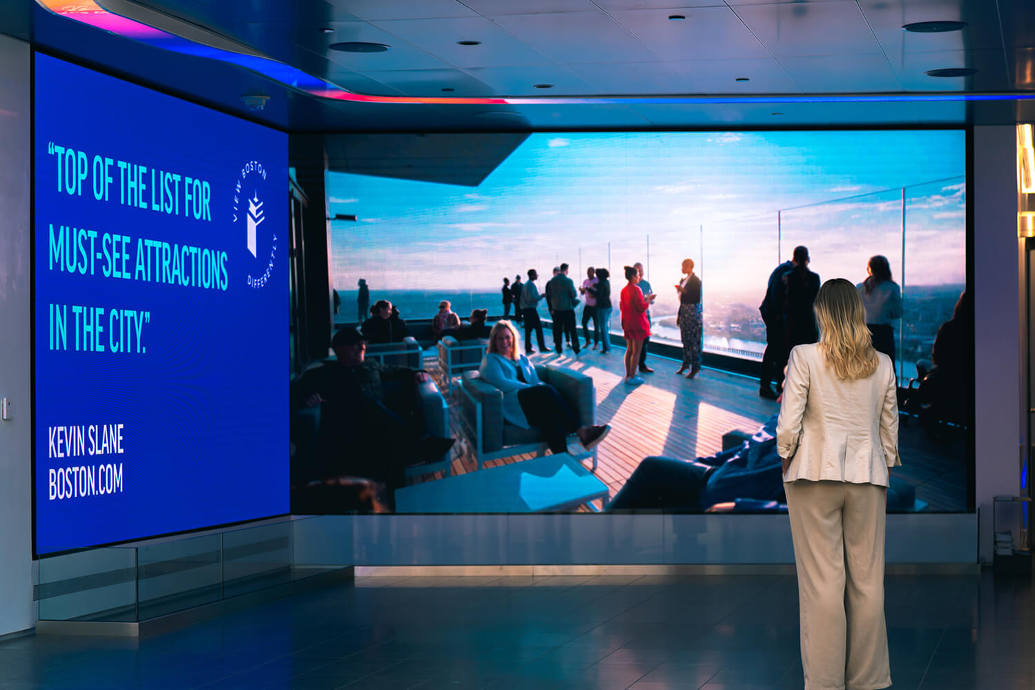 A woman staring at two large angular LED walls.