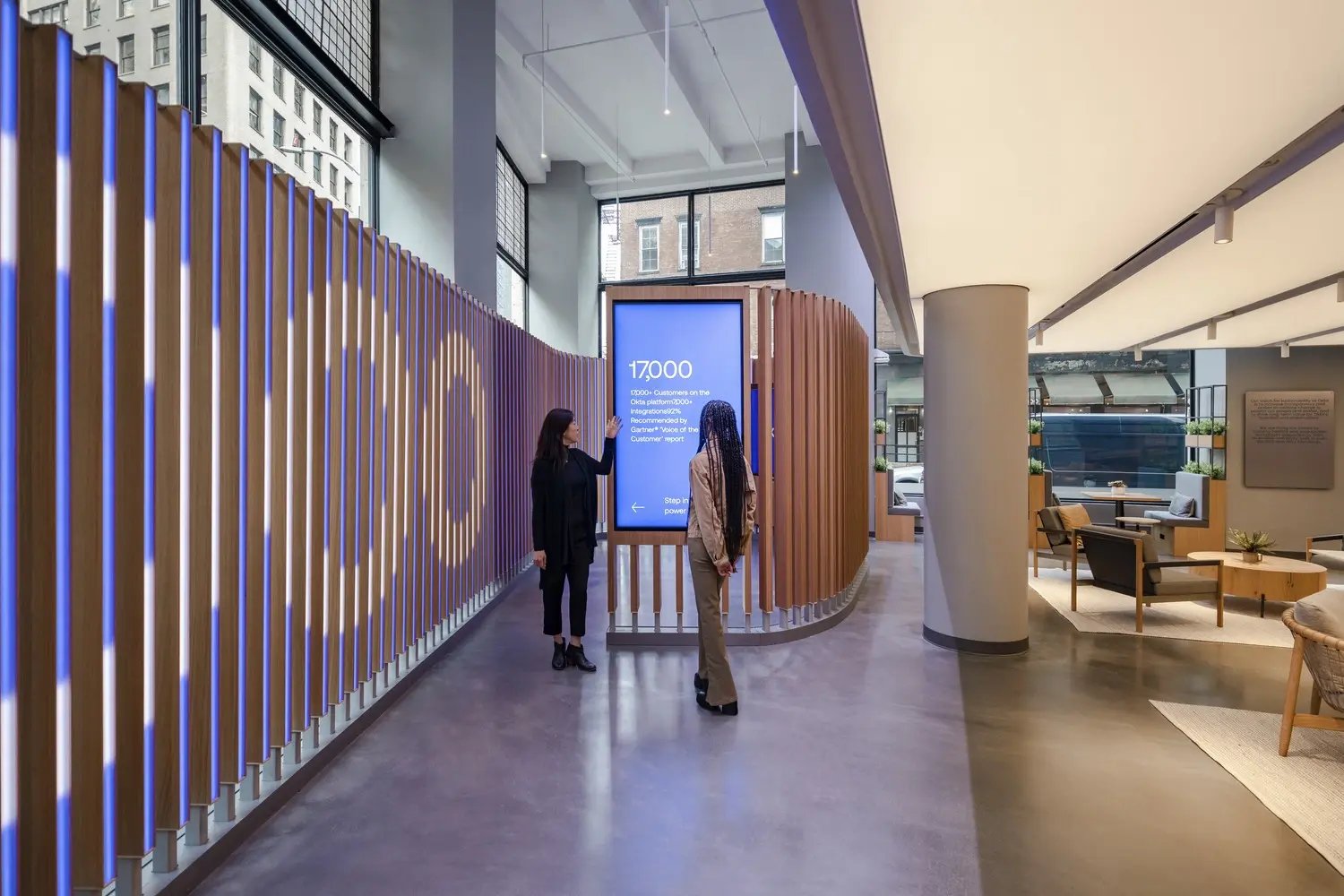 Two people are positioned in front of a large screen, possibly sharing ideas or information related to its content.