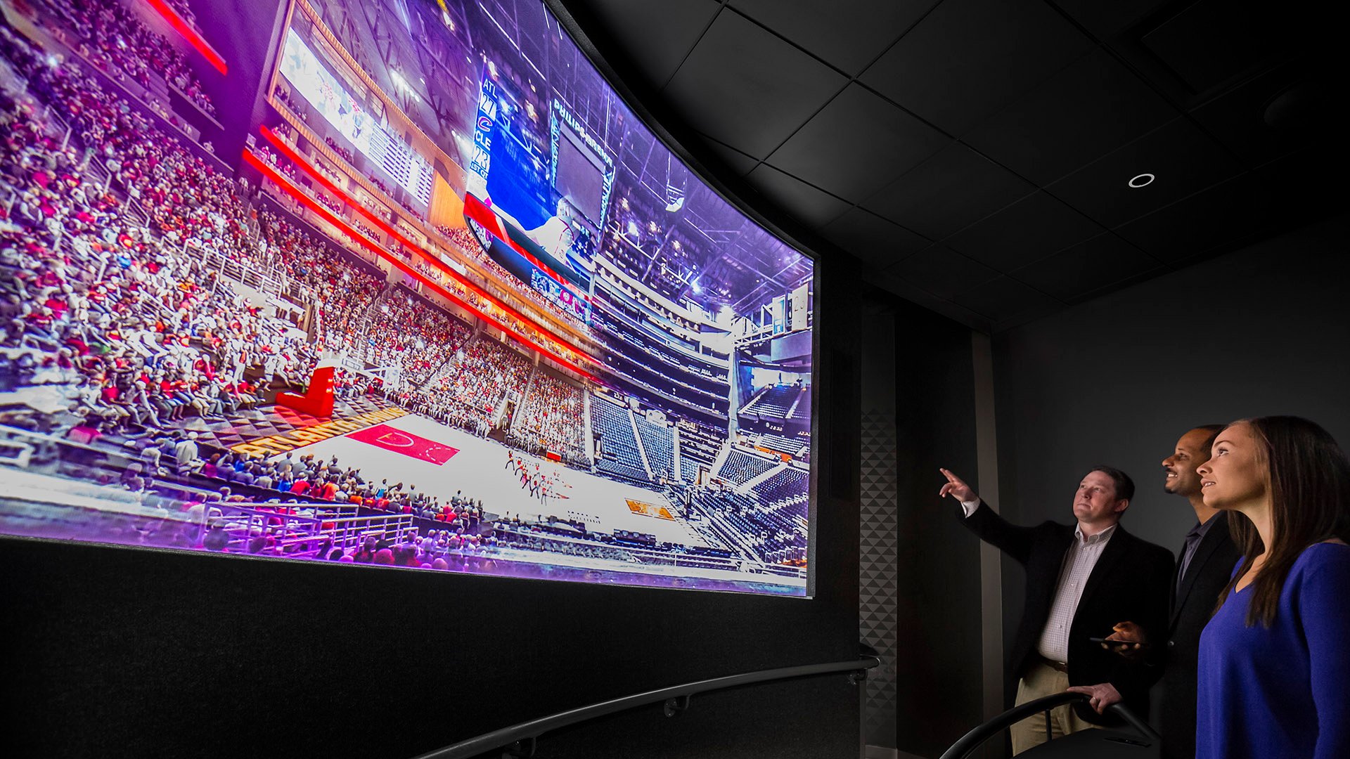 Three individuals stand in a sleek, modern exhibit space