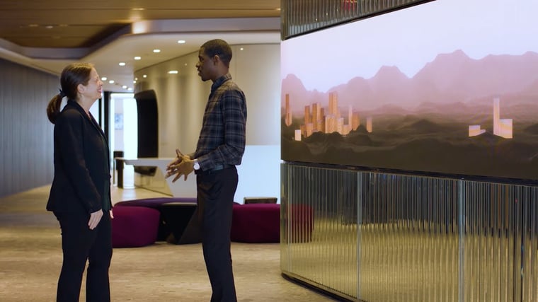 Two employees standing next to a video wall.