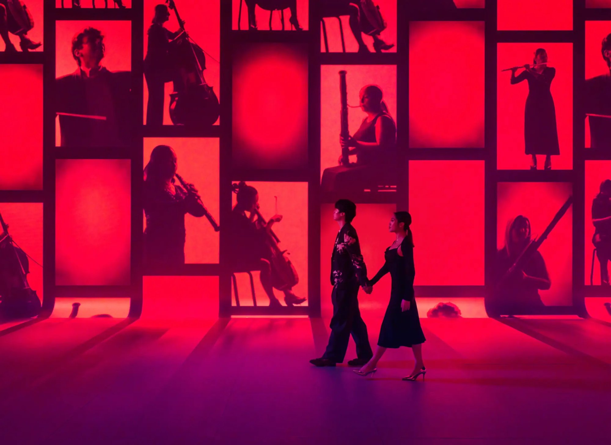 Two guests walking alongside red projection mapped content that extends from the ceiling to the floor.