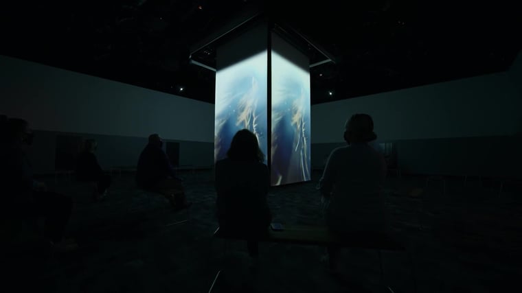 View of the Hall of Fame theater featuring a large central screens, dramatic lighting and immersive projections that highlight the history and heroes of Thoroughbred racing.