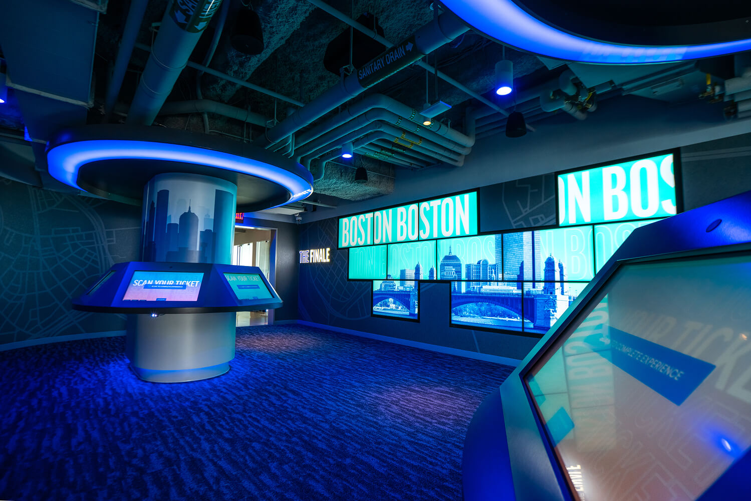 Interactive touchscreens oriented in a circular pattern and an LED wall behind.